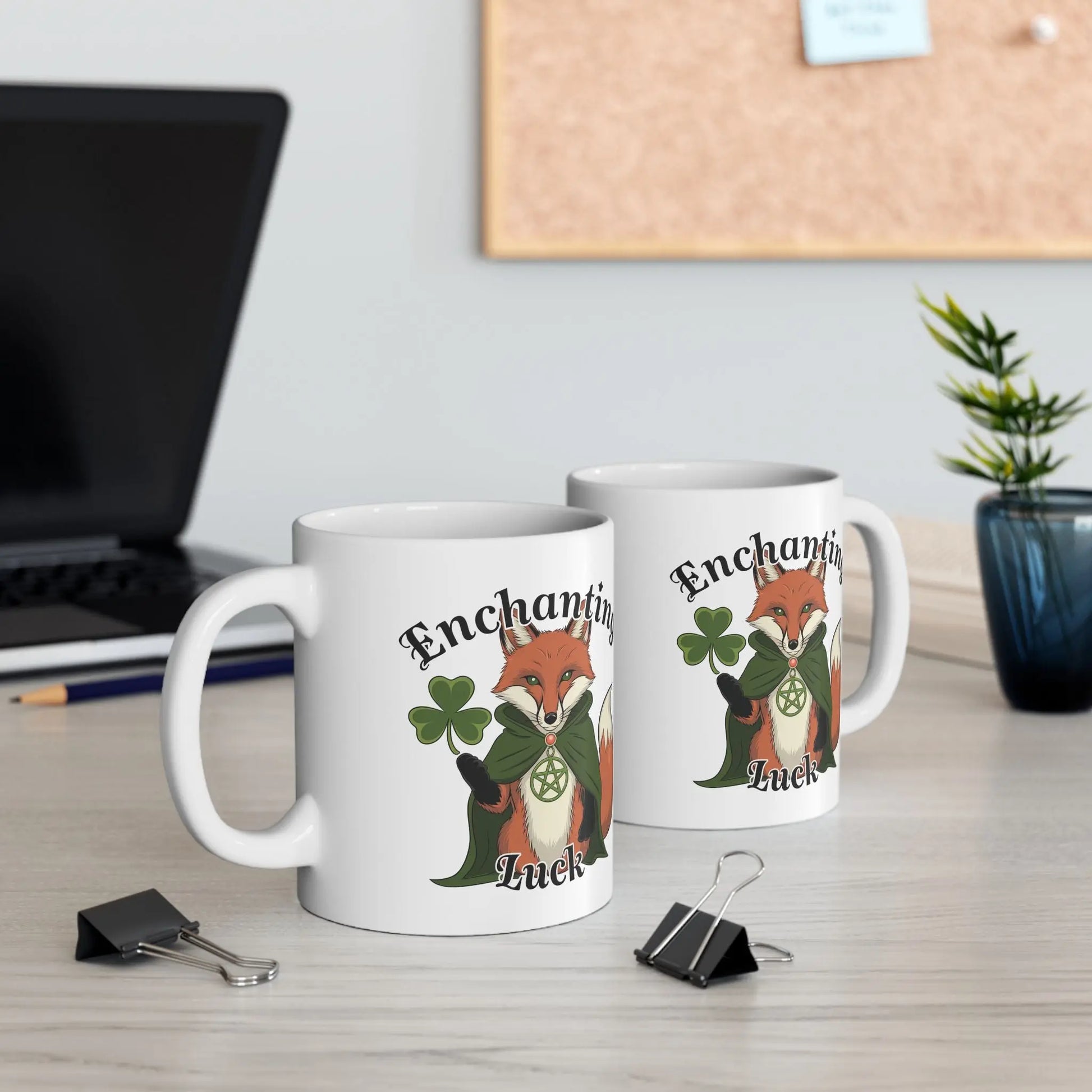 Mockup of a desk featuring two white fox mugs side by side, each displaying the mystical pagan fox design on opposite sides.