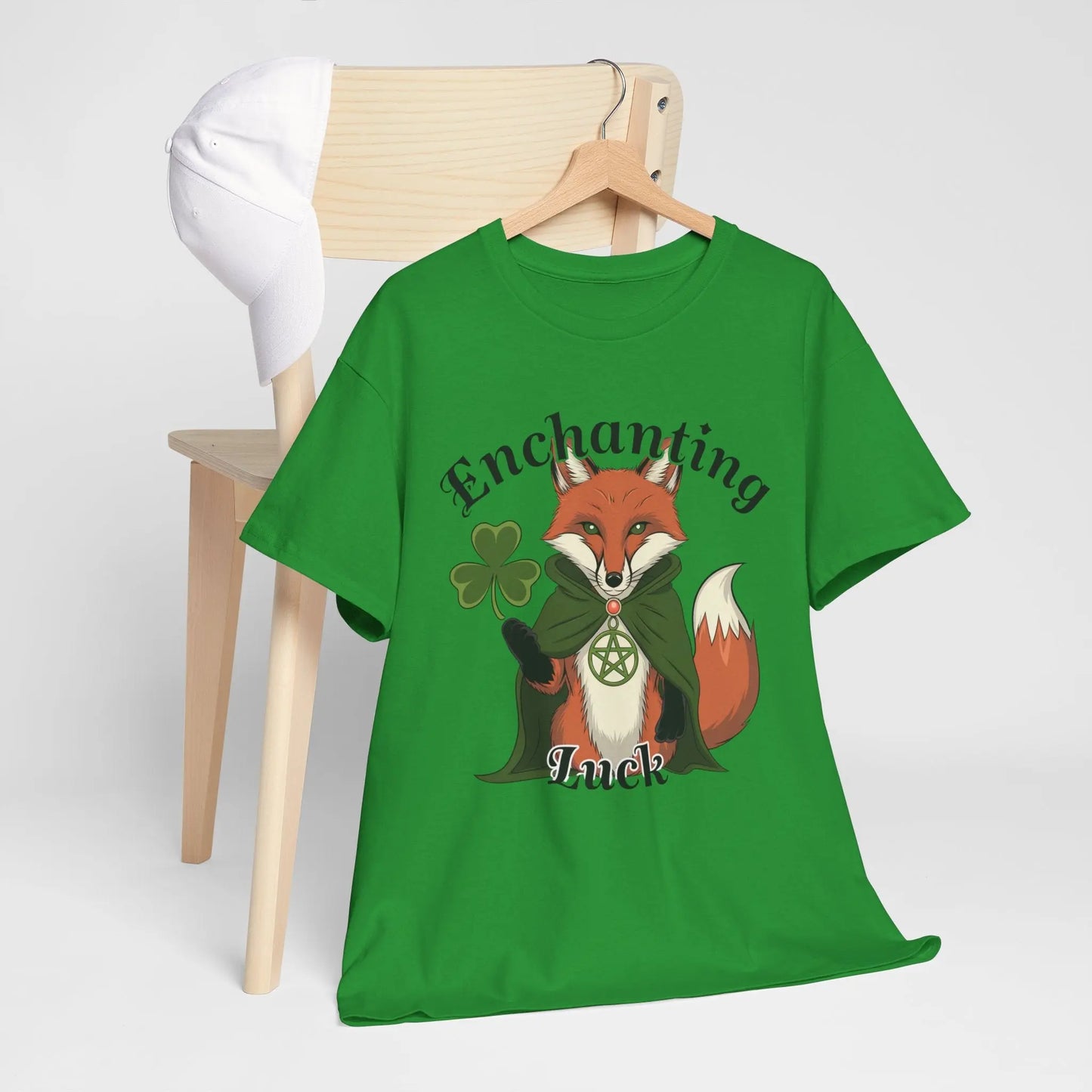 Hanging tee behind a chair mockup, featuring an Irish Green tee with a fox design, four-leaf clover, pentagram necklace, and the words 'Enchanting Luck.' witchypets.com